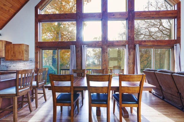 dining area with wood ceiling, high vaulted ceiling, and light wood-type flooring