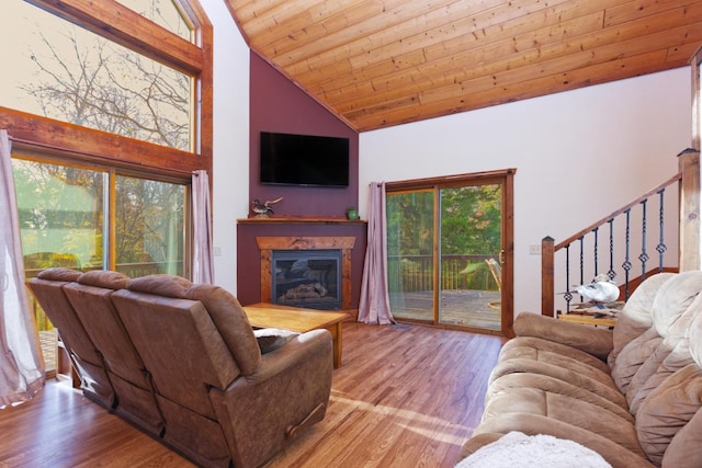 living room featuring a premium fireplace, light hardwood / wood-style flooring, a healthy amount of sunlight, and high vaulted ceiling