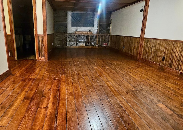 empty room with hardwood / wood-style flooring and wooden walls