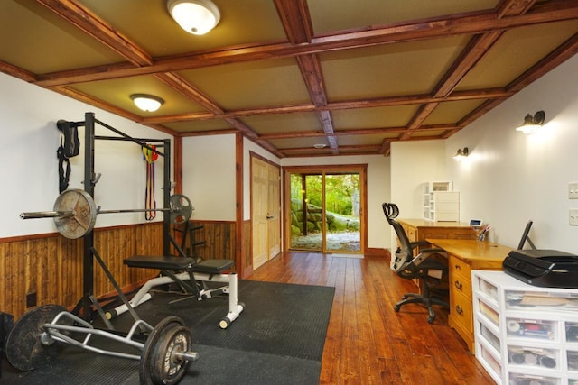 exercise room with wood walls, coffered ceiling, and dark hardwood / wood-style flooring