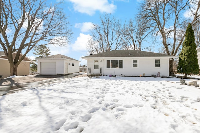 snow covered back of property featuring a garage and an outbuilding