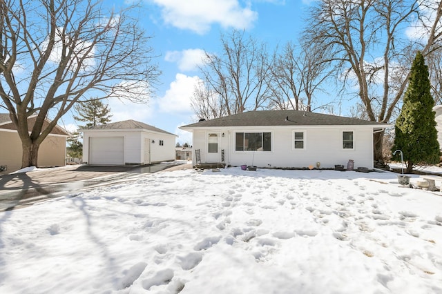 snow covered rear of property featuring an outdoor structure and a detached garage