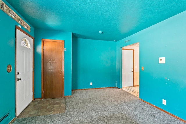 carpeted foyer with baseboards, a textured ceiling, and baseboard heating