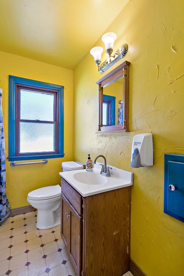 bathroom featuring vanity, baseboards, tile patterned floors, toilet, and a chandelier