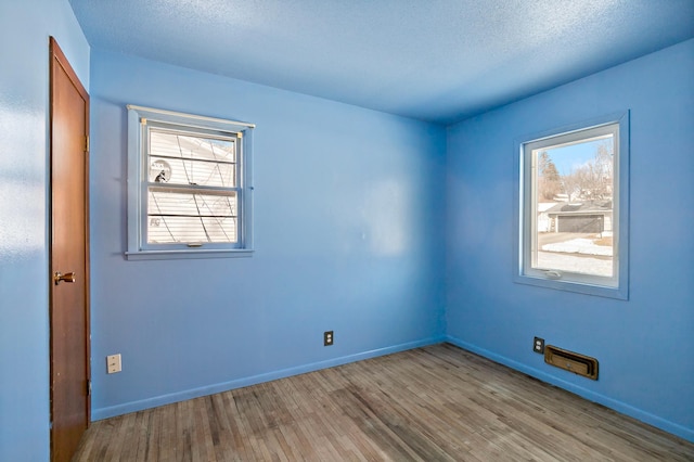 empty room featuring wood finished floors, baseboards, and a textured ceiling