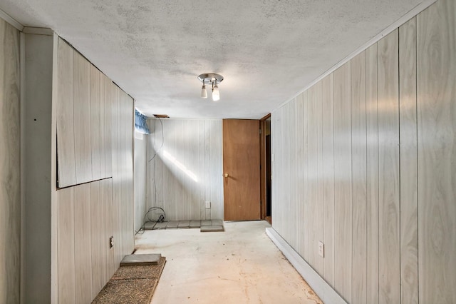 empty room with wooden walls, a textured ceiling, and concrete flooring