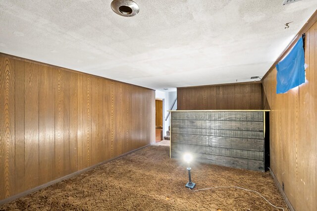 interior space with carpet flooring, wood walls, and a textured ceiling