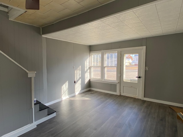 unfurnished living room featuring stairs, baseboards, and wood finished floors