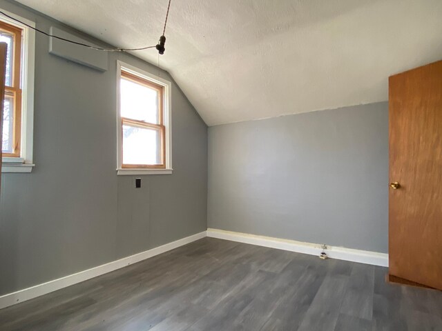 bonus room featuring baseboards, plenty of natural light, lofted ceiling, and dark wood-type flooring