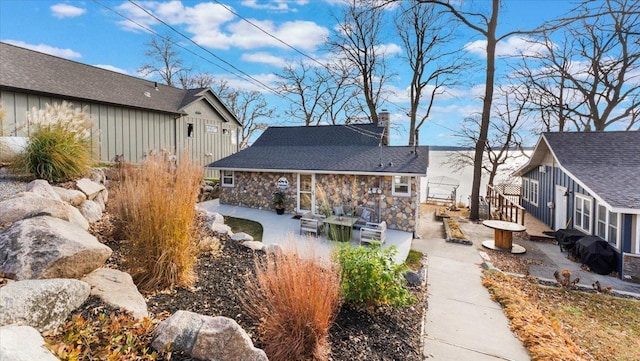 11470 Forada Beach Rd SE, Alexandria, MN 56308 - back of property with board and batten siding, a chimney, a patio area, an outdoor structure, and stone siding