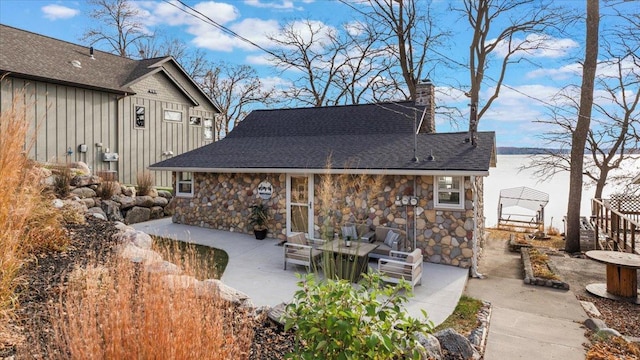 11470 Forada Beach Rd SE, Alexandria, MN 56308 - rear view of house with board and batten siding, a chimney, a patio area, and stone siding