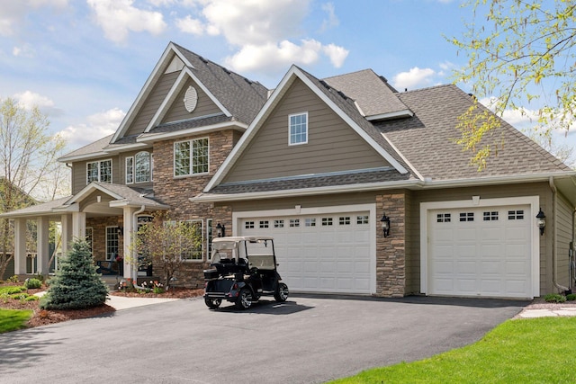 craftsman house featuring driveway, stone siding, a shingled roof, and an attached garage