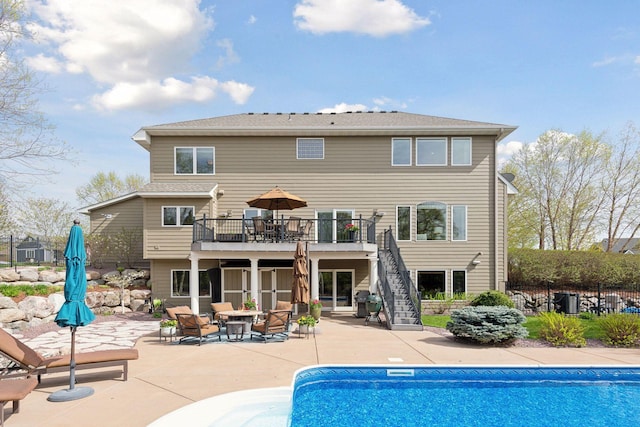 rear view of property featuring a fenced in pool, a patio area, fence, and stairs