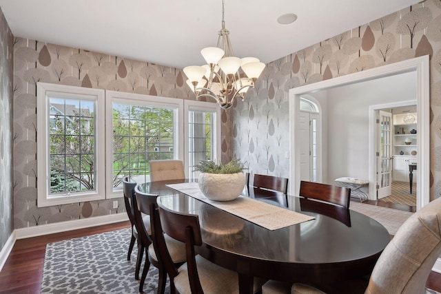 dining area featuring an inviting chandelier, dark wood-style flooring, baseboards, and wallpapered walls