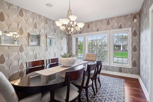 dining area with wallpapered walls, a notable chandelier, baseboards, and dark wood-type flooring