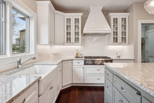 kitchen featuring premium range hood, glass insert cabinets, white cabinets, and light stone counters