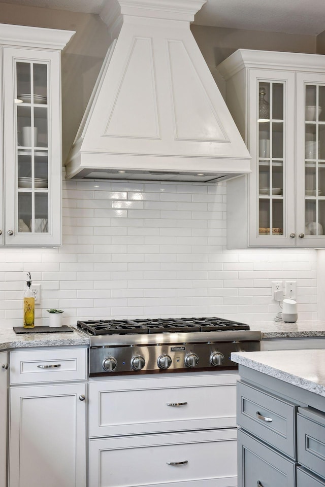 kitchen with glass insert cabinets, stainless steel gas stovetop, and white cabinetry