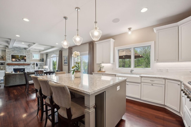 kitchen featuring a center island, white cabinetry, hanging light fixtures, and a sink