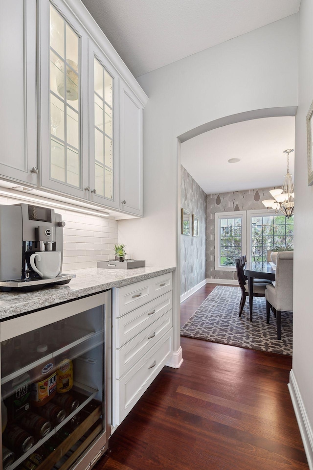 bar with wallpapered walls, baseboards, dark wood finished floors, wine cooler, and decorative light fixtures