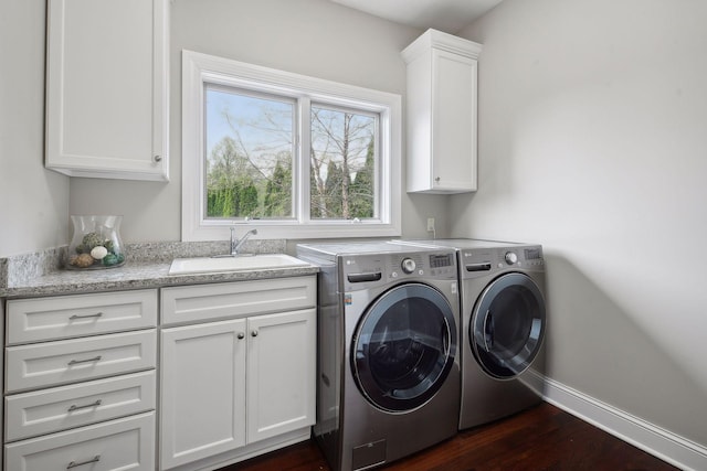 washroom featuring dark wood-style flooring, a sink, baseboards, cabinet space, and washing machine and clothes dryer