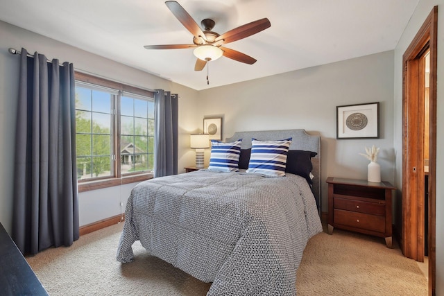 bedroom with light carpet, a ceiling fan, and baseboards