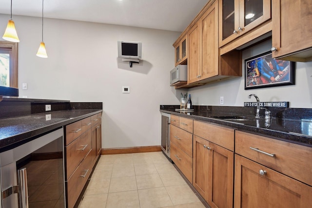 kitchen with beverage cooler, glass insert cabinets, brown cabinets, hanging light fixtures, and a sink