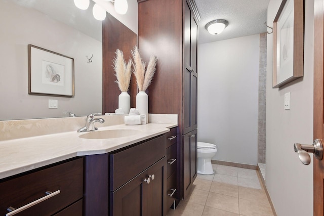 bathroom featuring baseboards, toilet, tile patterned floors, a textured ceiling, and vanity