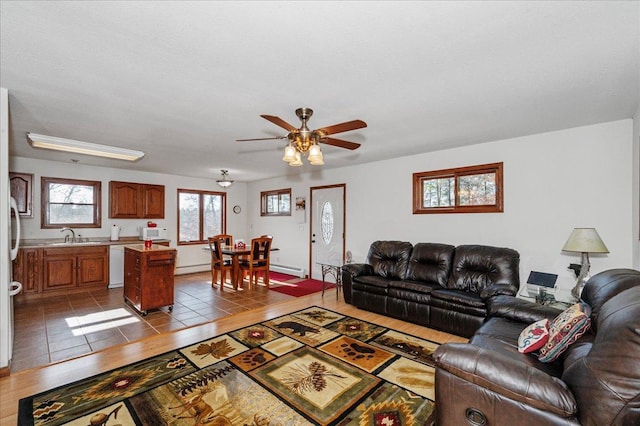 tiled living room with a baseboard radiator, sink, and ceiling fan