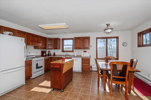 kitchen featuring a baseboard radiator, sink, a center island, and white appliances