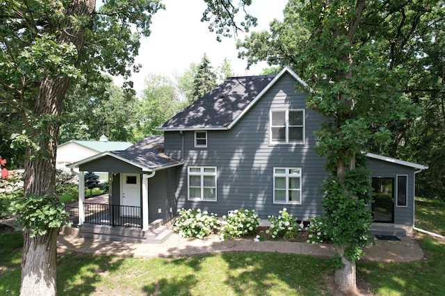 back of house featuring covered porch and a lawn