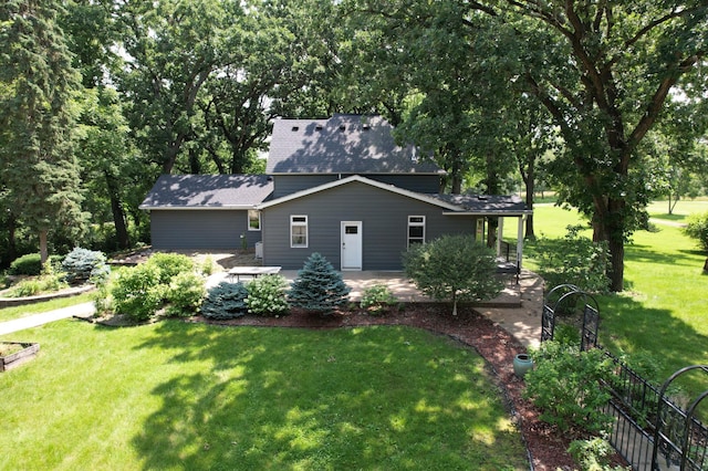 view of front of home featuring roof with shingles, a patio, and a front lawn