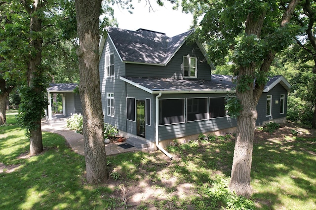 view of front of home featuring a shingled roof, a sunroom, and a front lawn