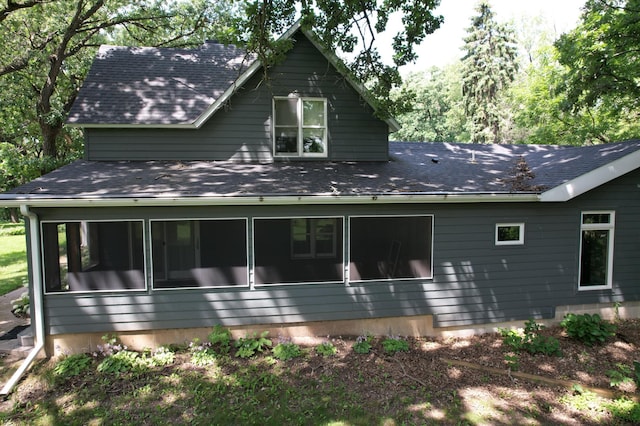rear view of property featuring a sunroom and roof with shingles