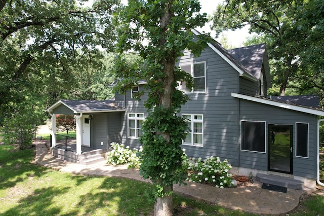 back of property featuring a yard and covered porch