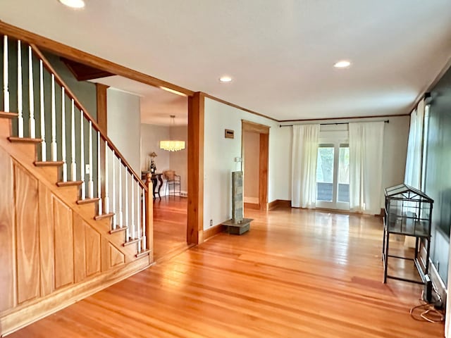 unfurnished living room featuring stairs, a notable chandelier, recessed lighting, and wood finished floors