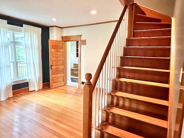 stairs with ornamental molding and hardwood / wood-style floors