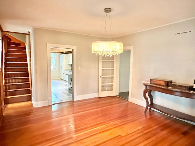 dining area with a notable chandelier, baseboards, crown molding, wood finished floors, and stairway