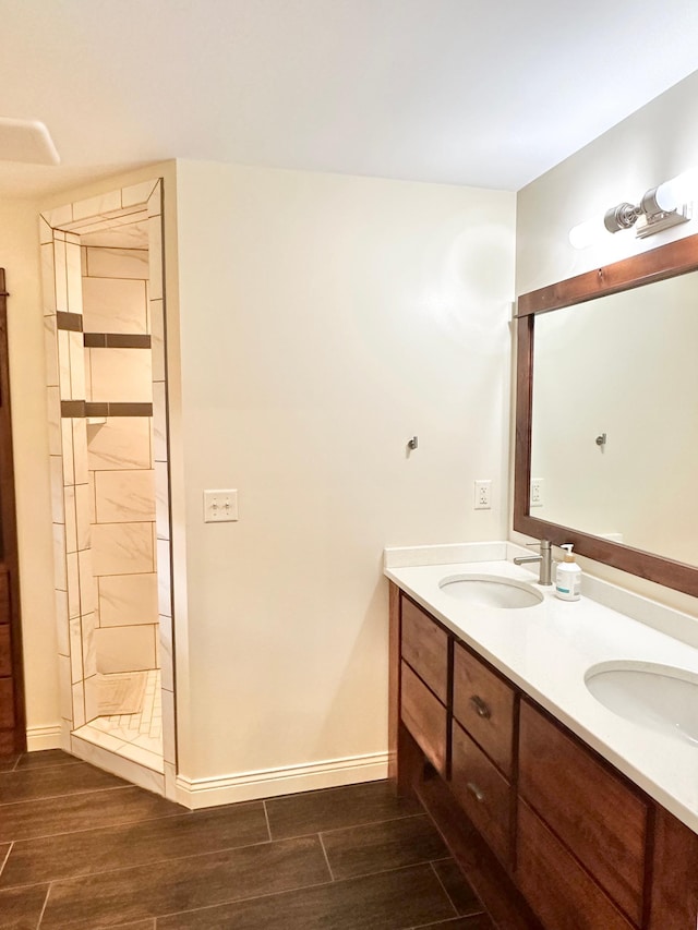full bathroom with baseboards, double vanity, a sink, and wood finished floors