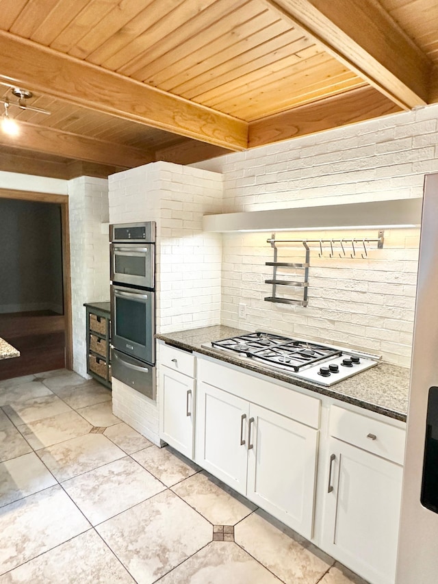 kitchen featuring white gas stovetop, stainless steel double oven, beamed ceiling, wooden ceiling, and white cabinetry