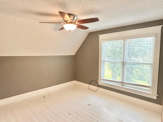 additional living space featuring ceiling fan, a textured ceiling, lofted ceiling, and light hardwood / wood-style flooring