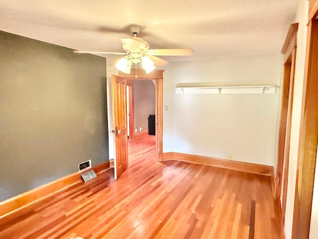 spare room with ceiling fan, baseboards, visible vents, and wood finished floors