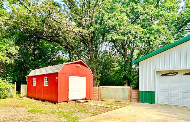 view of outbuilding featuring an outbuilding, driveway, and fence