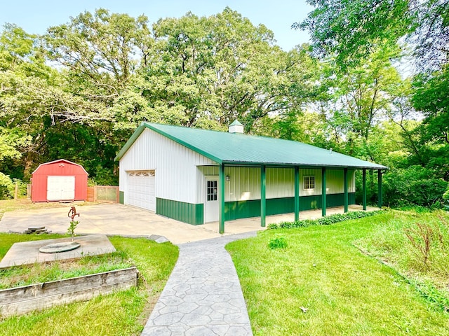 view of front facade featuring a garage, metal roof, an outdoor structure, a front yard, and a shed