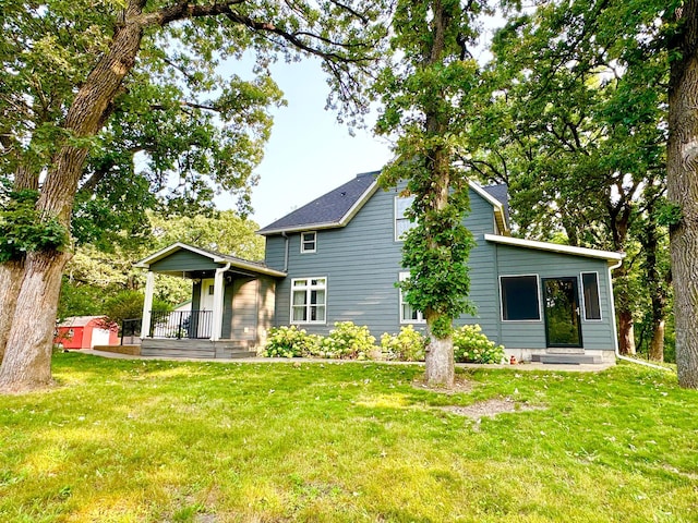 rear view of property featuring a storage shed, a yard, an outdoor structure, and a porch