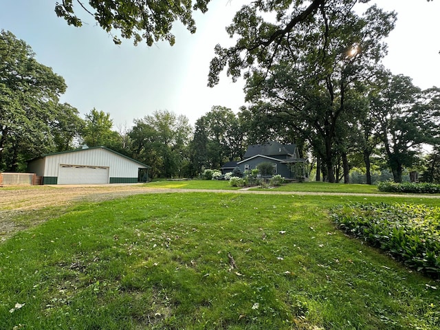 view of yard with a garage, an outbuilding, and driveway