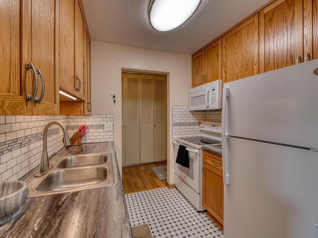 kitchen with sink, backsplash, a textured ceiling, and white appliances