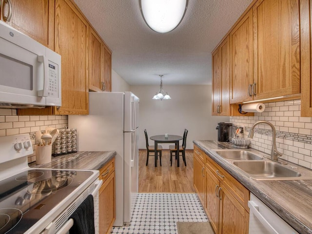 kitchen with pendant lighting, sink, white appliances, and a textured ceiling