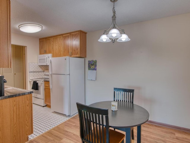 kitchen with white appliances, light hardwood / wood-style floors, decorative backsplash, a textured ceiling, and decorative light fixtures