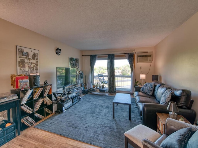 living room with a wall mounted air conditioner, hardwood / wood-style floors, and a textured ceiling