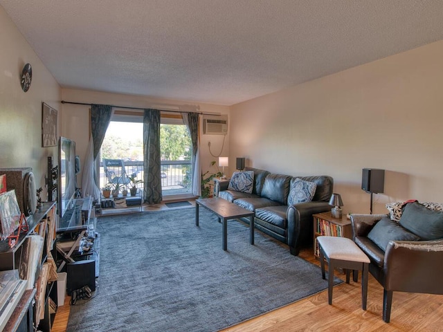 living room featuring hardwood / wood-style flooring, a textured ceiling, and an AC wall unit